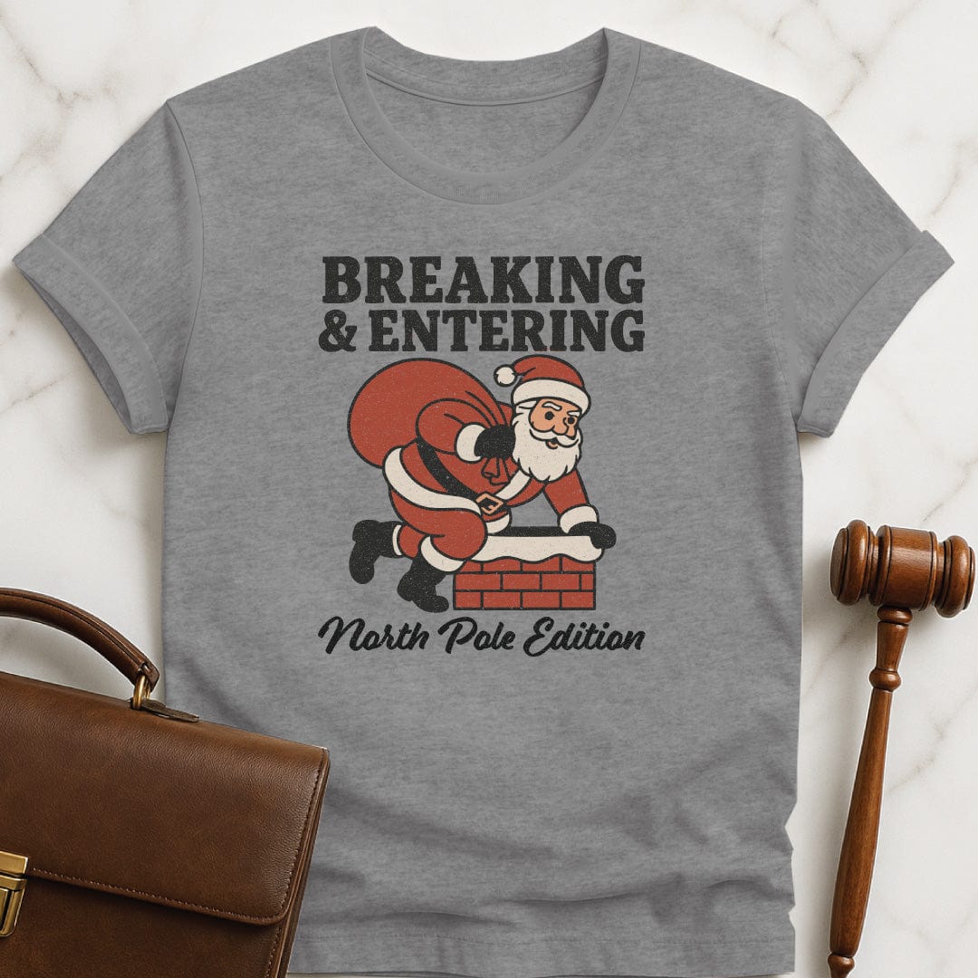 santa lawyer graphic t shirt that says Breaking and entering North Pole edition featuring Santa Claus going down a chimney in grey