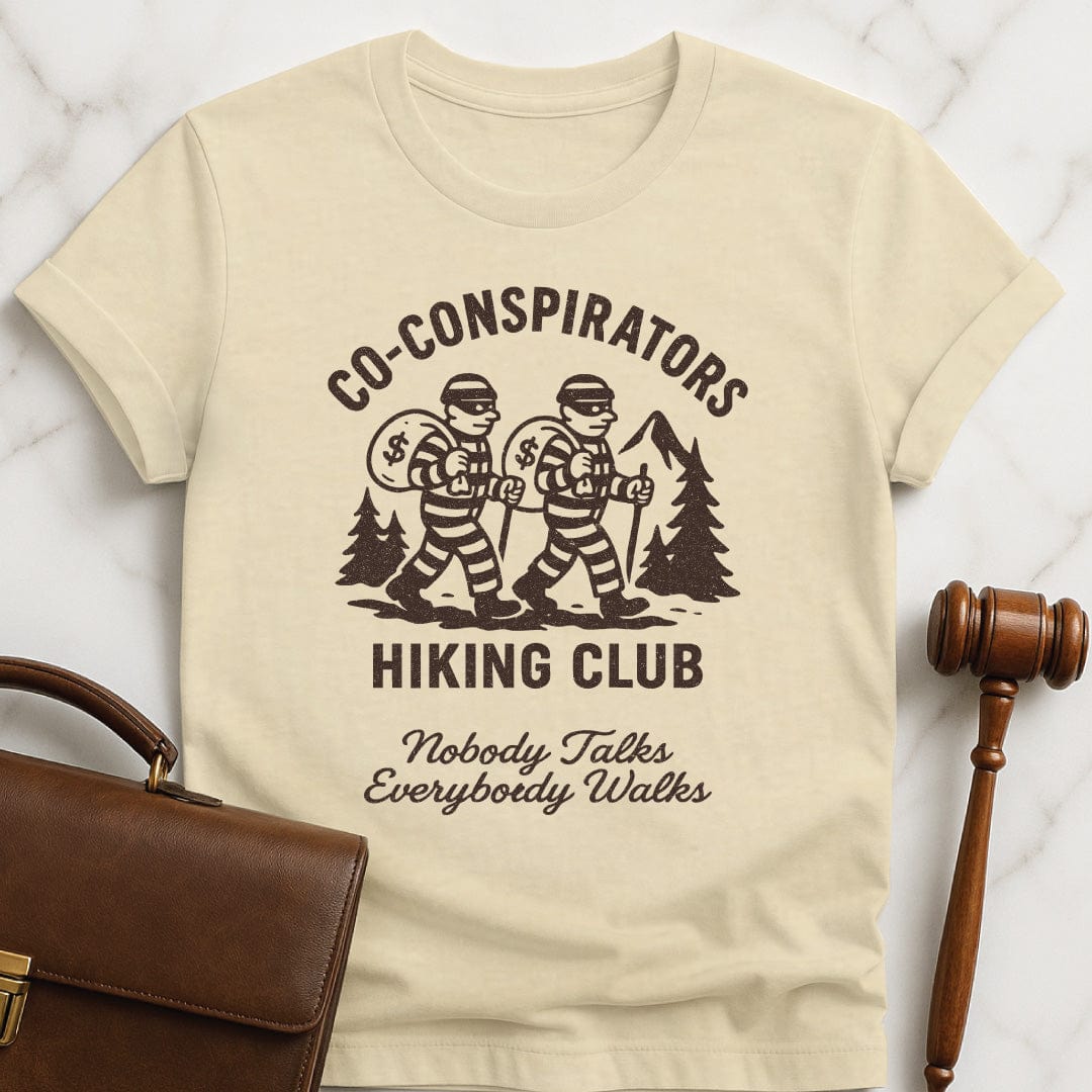 cool law school tee that says Co-Conspirators Hiking Club Nobody Talks Everybody Walks featuring robbers carrying bags of money on a hike in cream