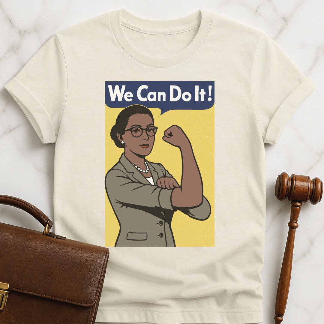 feminist new lawyer t shirt that says We can do it featuring a woman in a suit posing like Rosie the Riveter with a yellow background in cream
