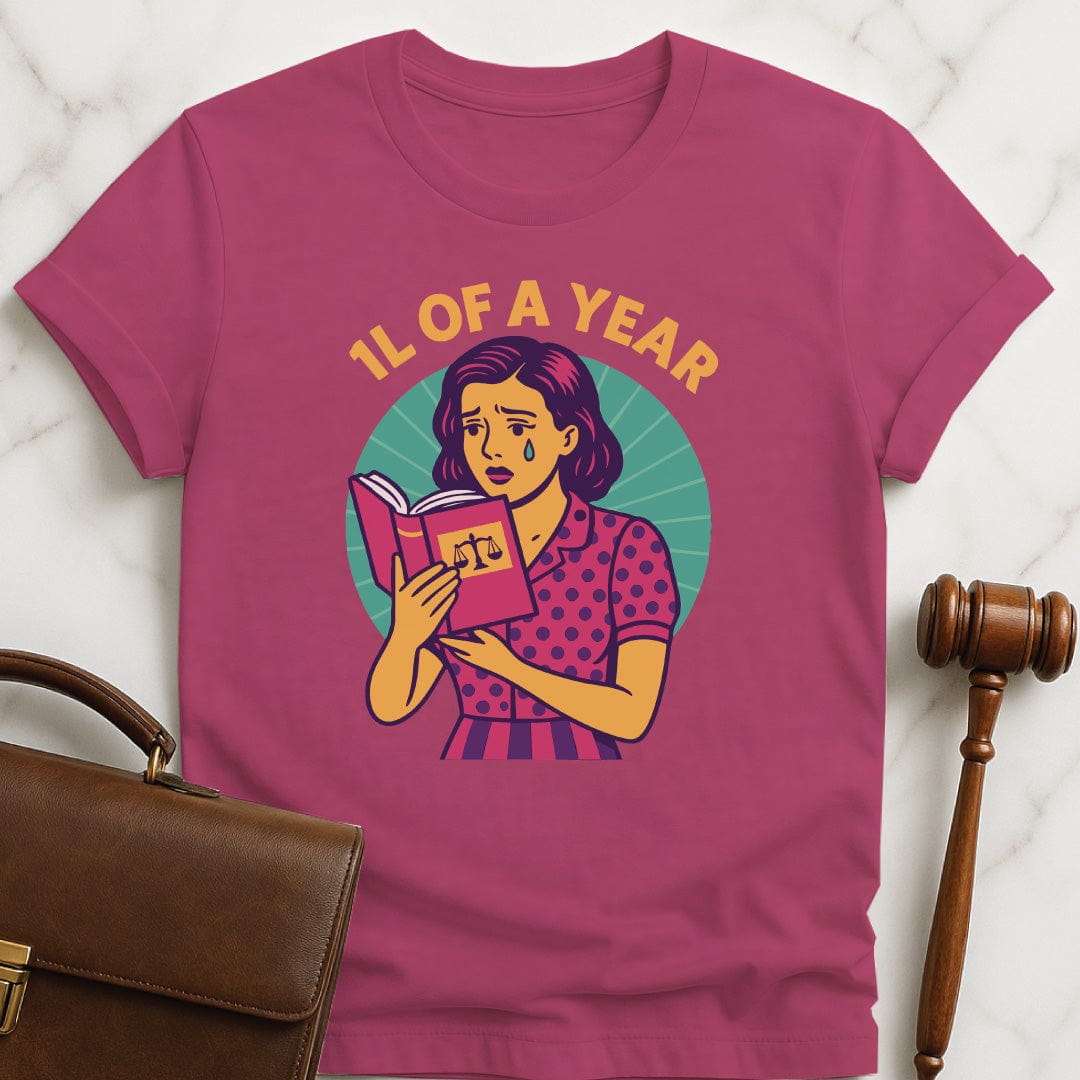 cool law school graphic t shirt that says 1L of a Year featuring comic book woman holding a law textbook and crying in pink