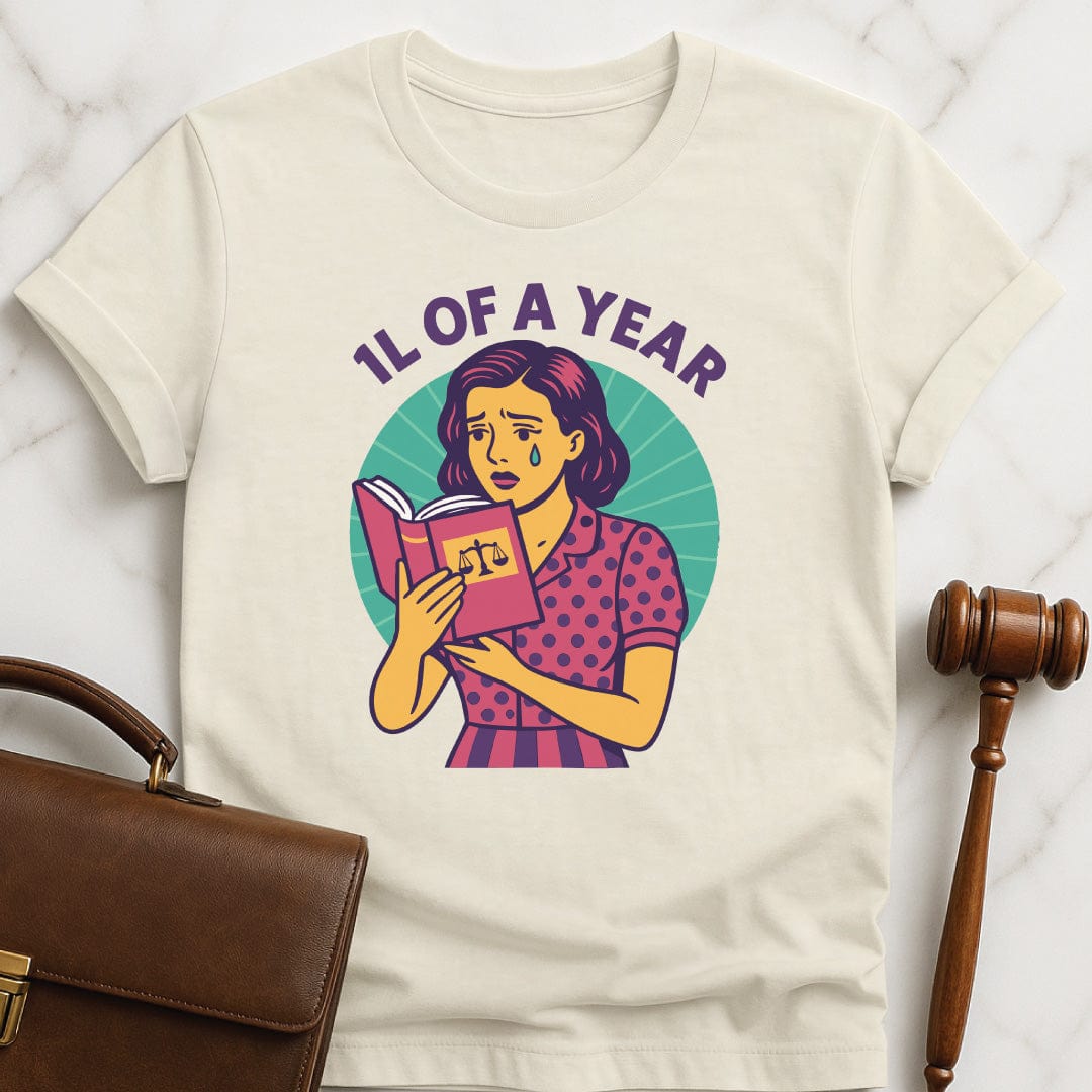 cool law school graphic tee that says 1L of a Year featuring comic book woman holding a law textbook and crying in cream