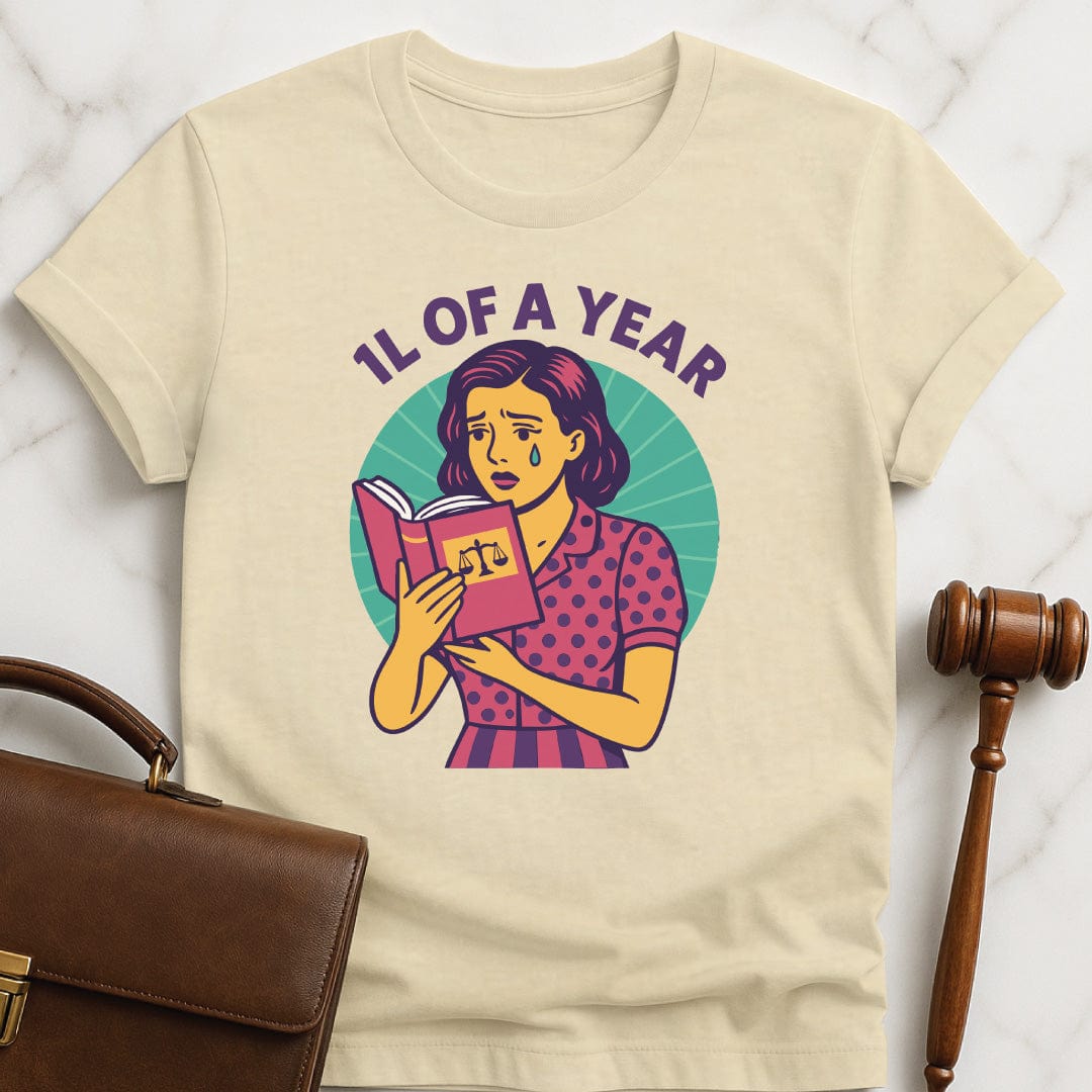 cool law school graphic t shirt that says 1L of a Year featuring comic book woman holding a law textbook and crying in cream