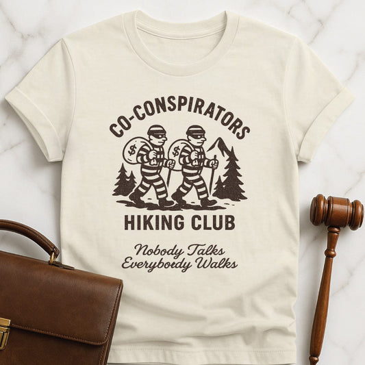 cool law school graduate graphic t shirt that says Co-Conspirators Hiking Club Nobody Talks Everybody Walks featuring robbers carrying bags of money on a hike in cream