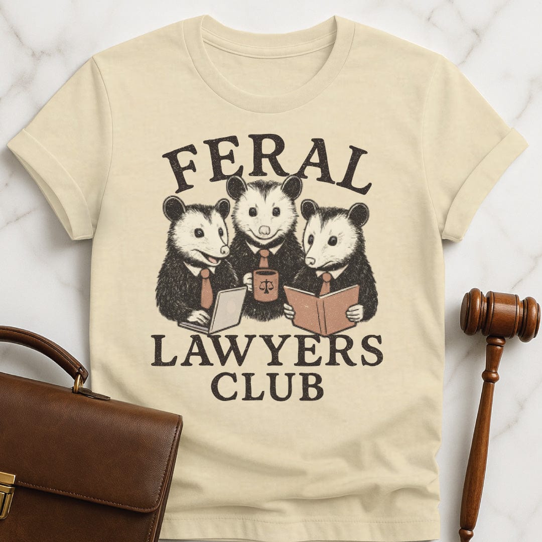 cute attorney graphic t-shirt that says feral lawyers club featuring three possums in business suits and a briefcase in cream