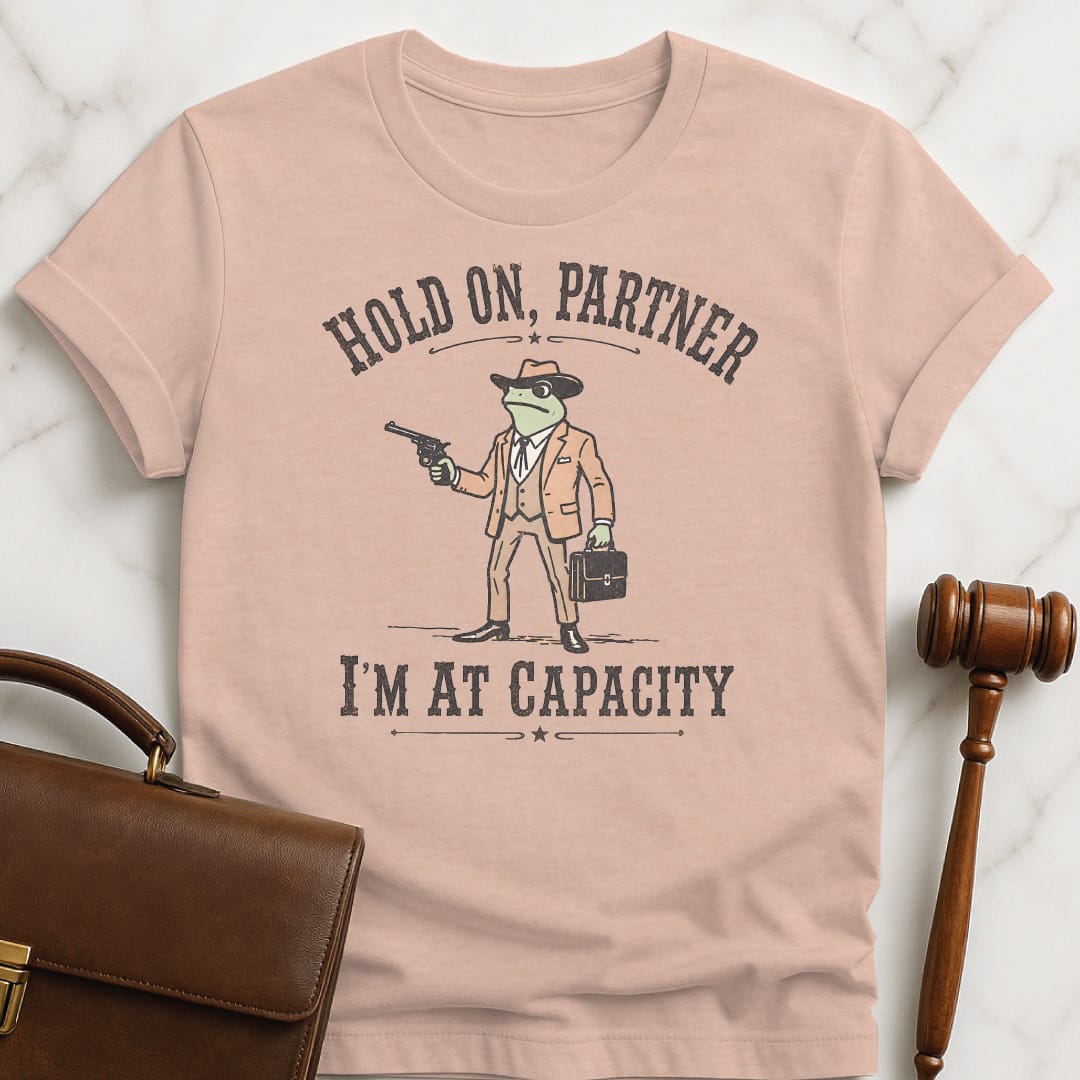 cool law grad tshirt that says Hold on partner Im at capacity featuring cowboy lawyer toad or frog holding a gun and briefcase in heather peach