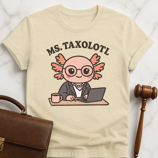funny new attorney graphic t-shirt that says Ms Taxolotl featuring axolotol in a business suit and pearls at a desk with a laptop and a mug in cream