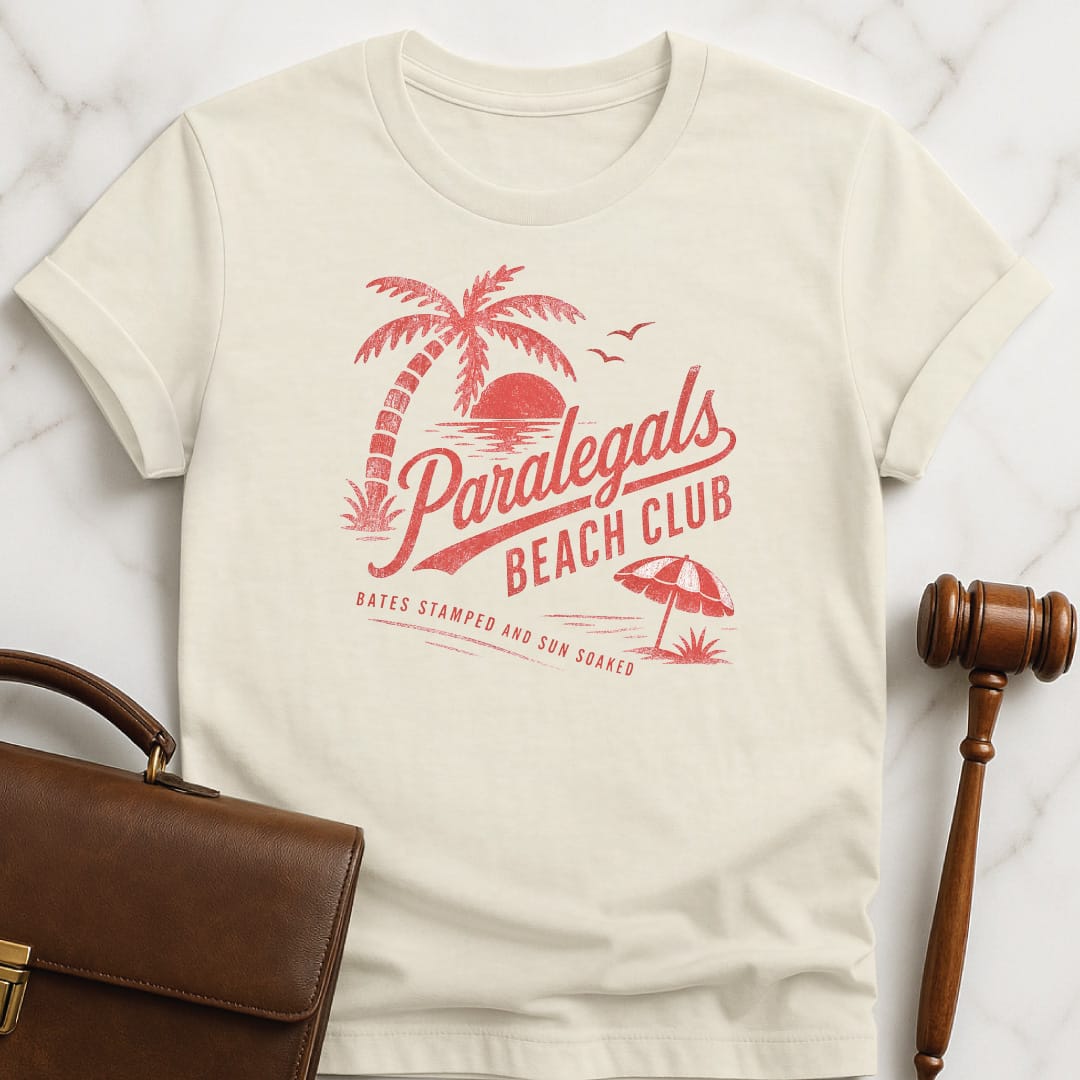 funny lawyer graphic t-shirt that says paralegals beach club bates stamped and sun soaked featuring beach scene in cream