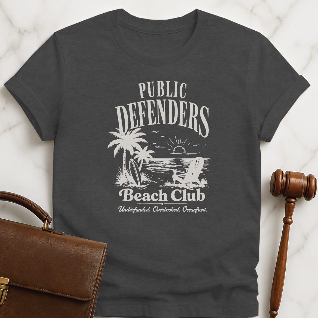 funny lawyer graphic tshirt that says Public defenders beach club underfunded overbooked oceanfront featuring beach with palm trees and beach chairs in grey