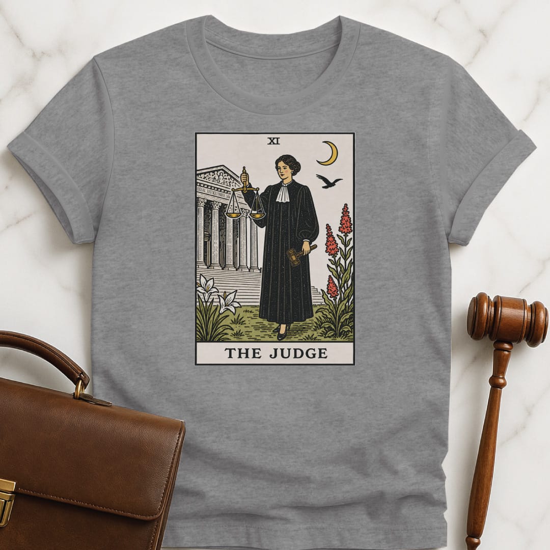 trendy new attorney graphic t shirt that says The Judge featuring tarot card style of a woman judge holding a scales of justice and gavel in front of courthouse in grey