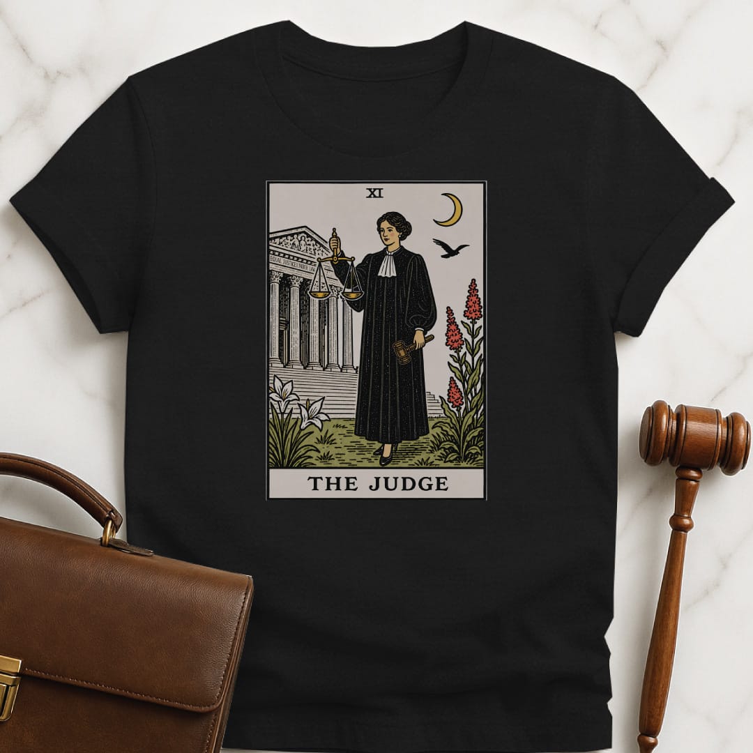 cool lawyer graphic tshirt that says The Judge featuring tarot card style of a woman judge holding a scales of justice and gavel in front of courthouse in black