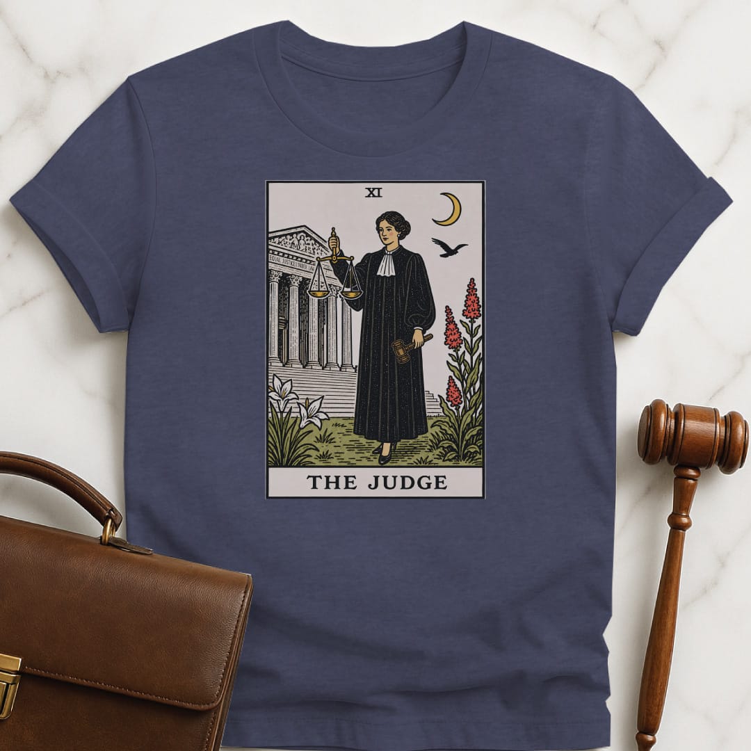 trendy attorney graphic tee that says The Judge featuring tarot card style of a woman judge holding a scales of justice and gavel in front of courthouse in heather blue