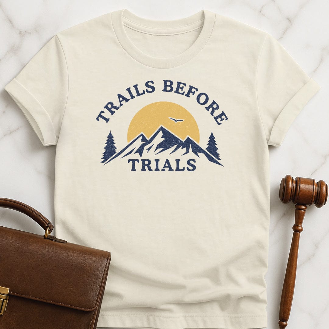 cool law graduate t-shirt that says trails before trials featuring mountain sun and a flying bird in cream
