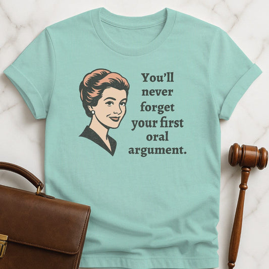 funny law student graphic t-shirt that says You Never Forget Your First Oral Argument featuring A retro woman in heather green